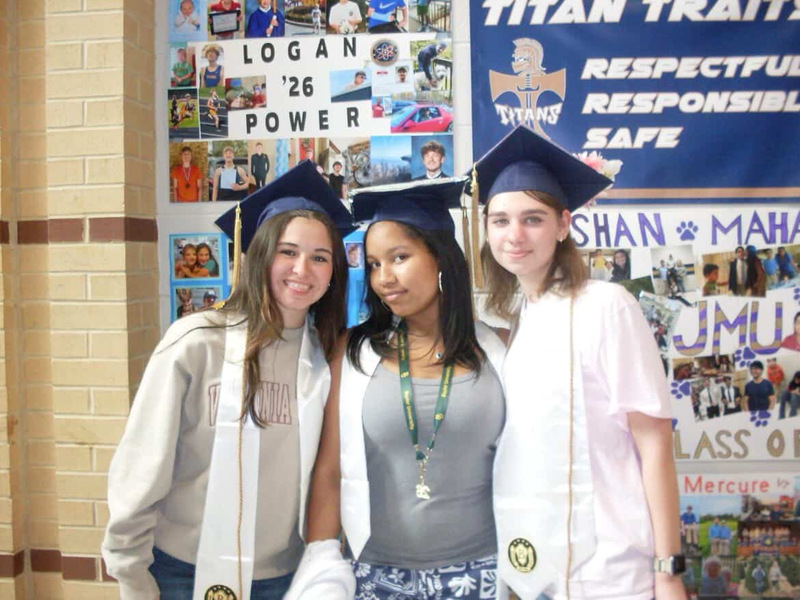 Taylor Malone poses with her friends in front of the senior wall